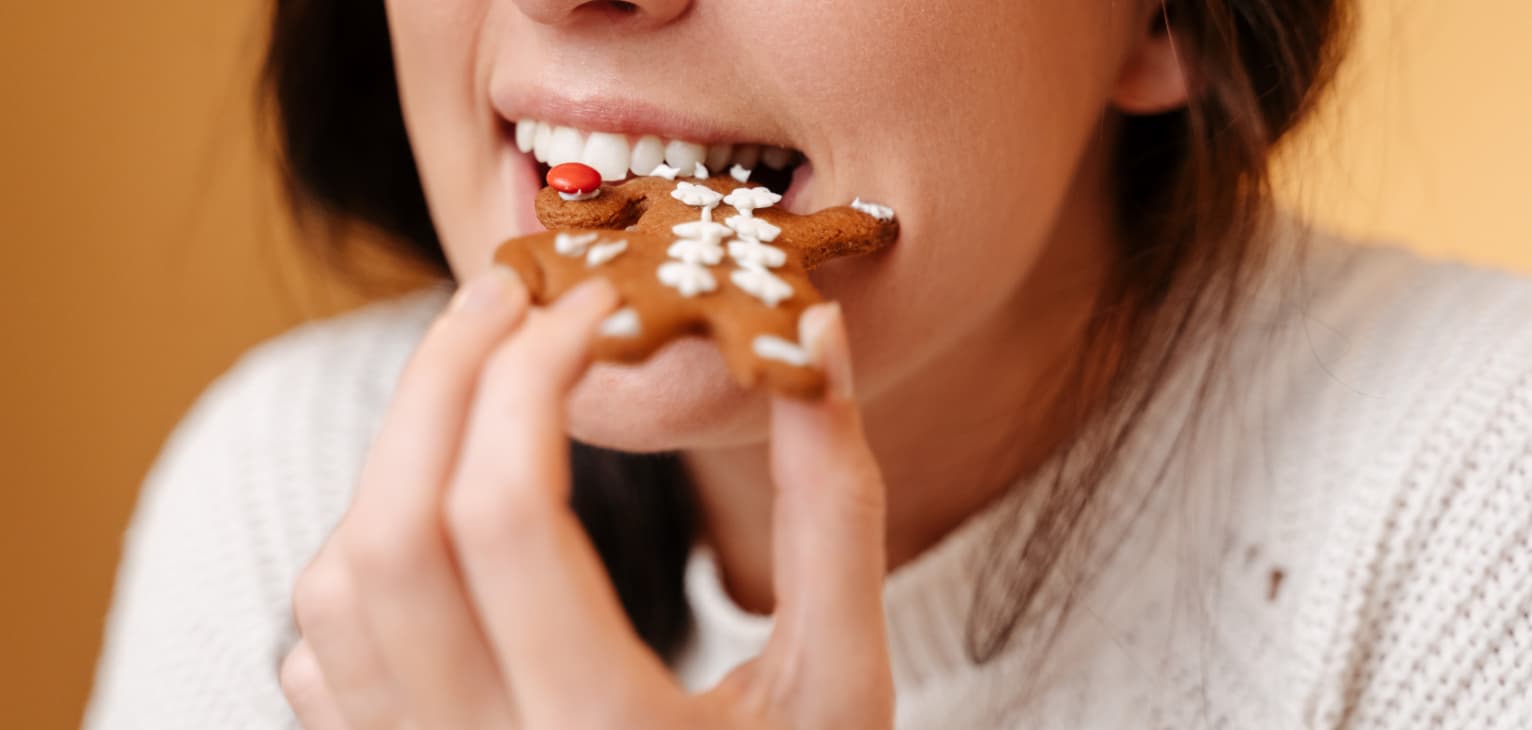 Woman with healthy teeth eating festive biscuit