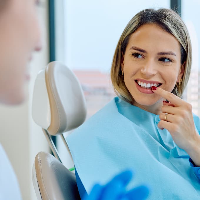 female patient sat in chair, discussing treatment with dentist