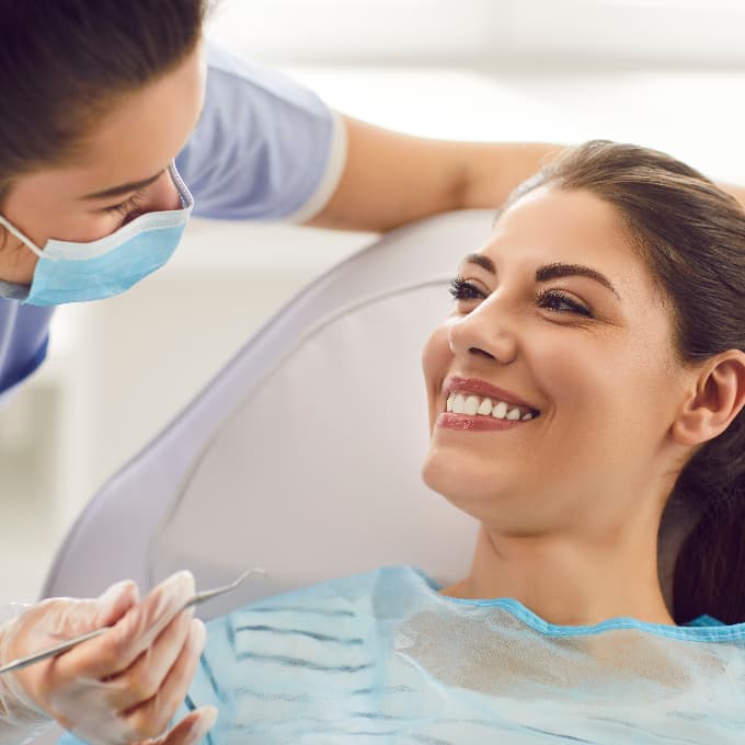 Smiling patient speaking with a dental professional during a routine dental appointment, discussing oral health and treatment options in a comfortable clinic setting.
