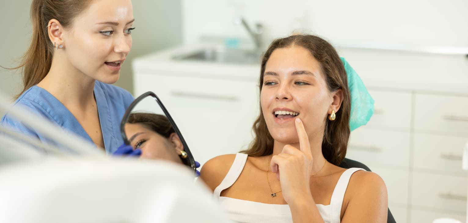 woman looking at teeth in mirror